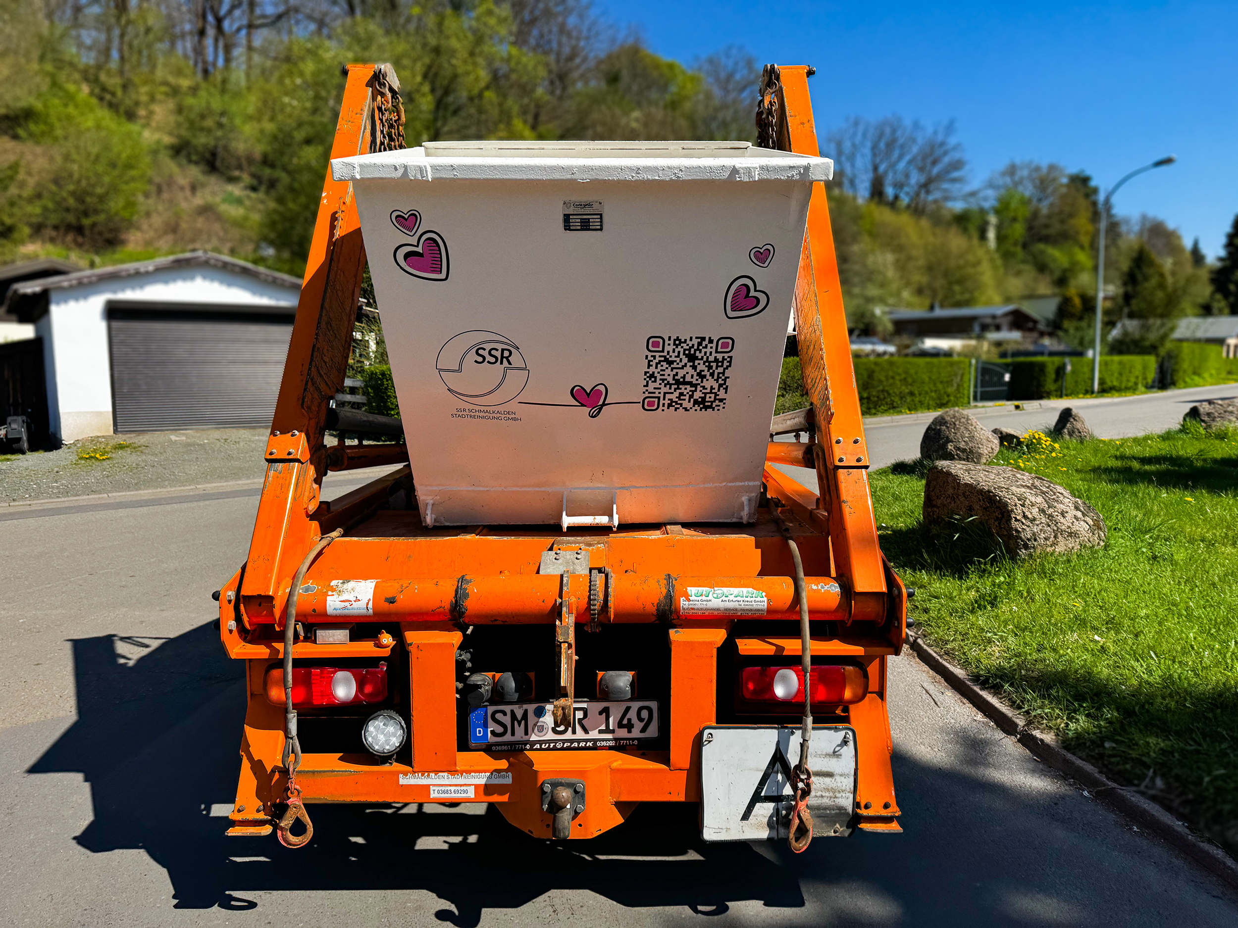 Weißer Container mit QR-Code und rosa Herzen auf Absetz-Fahrzeug