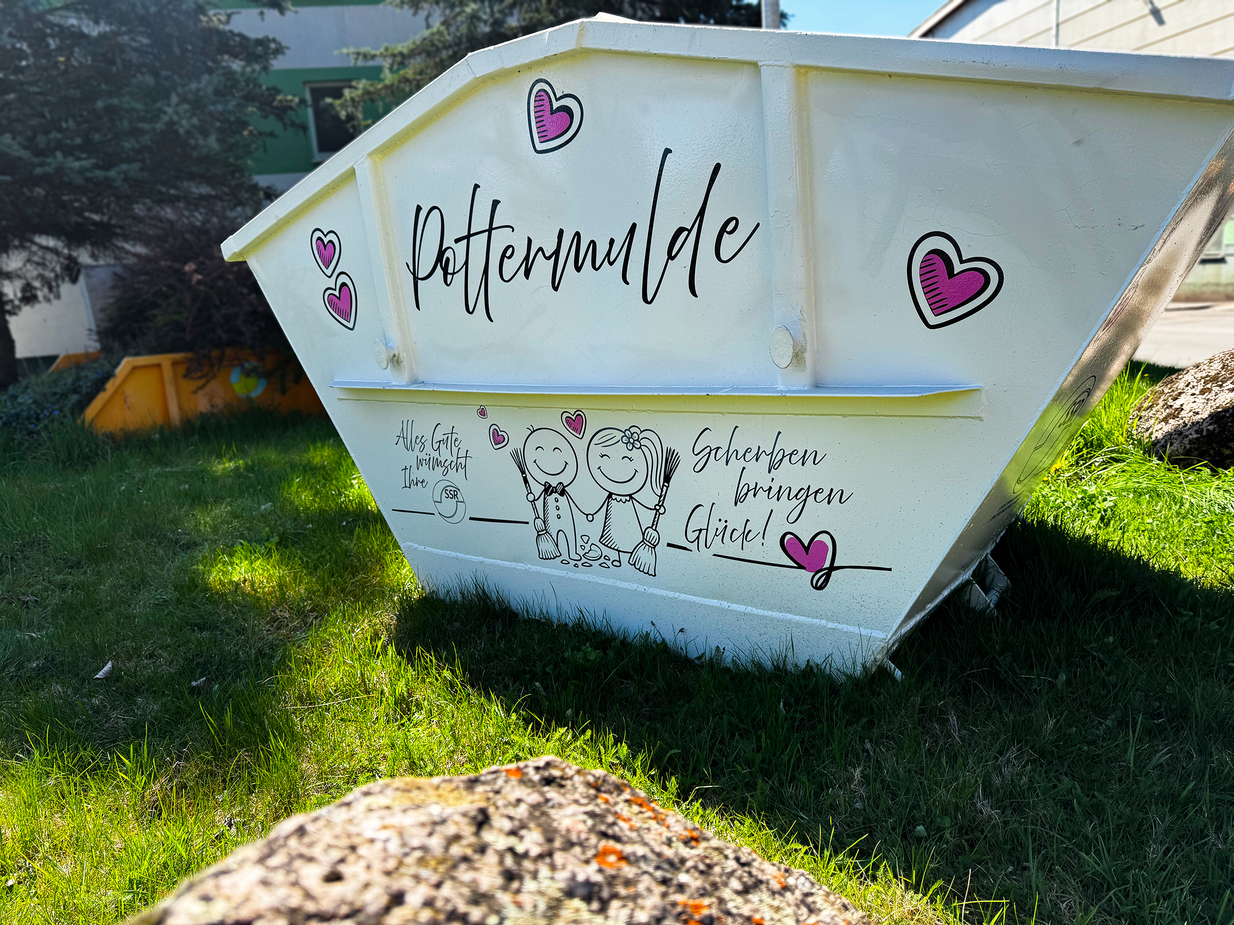 Weißer Container mit dem Aufdruck "Poltermulde" und rosa Herzen